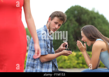 Cheater man cheating during a marriage proposal with his innocent girlfriend Stock Photo