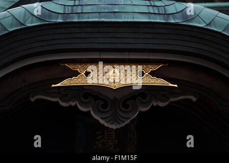 Japanese Asian temple shrine roof tile and center entrance detail in gold Stock Photo