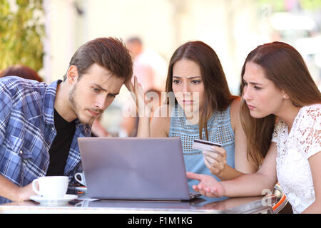 Three shopper friends buying online with credit card finance problems in a coffee shop Stock Photo