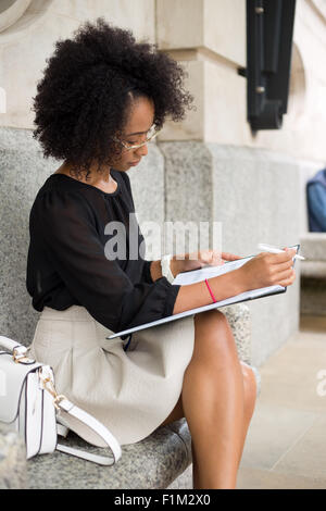 young woman in the city writing in her diary Stock Photo