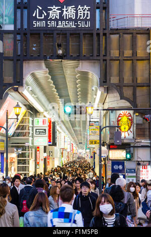 Ebisubashi bridge, packed with people during the evening blue hour with entrance to Shinsaibashi shopping street, a very long covered arcade. Stock Photo