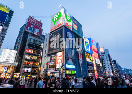 Japan, Osaka. Dotonbori, Ebisubashi bridge. View along buildings and skyline with giant billboards at Blue hour but before many signs are illuminated. Stock Photo