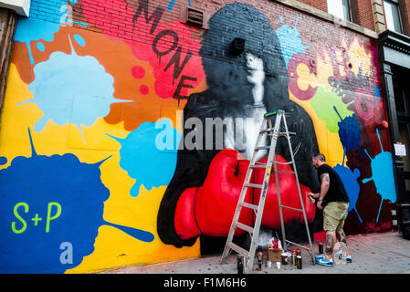 New York, NY - 3 September 2015 - Solus, of Crash and Solus, puts the finishing touches on a memorial mural for Joey Ramone, for the 40th Anniversary of punk rock club CBGB. The street mural is part of the  L.I.S.A Project whose mission it is to bring a diverse group of artists together in Little Italy on historic Mulberry Street to create Manhattan's only mural arts district. That dream has grown into a premiere public arts program reaching into SoHo, Lower Eastside, East Village, Chinatown and Chelsea. Stock Photo