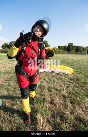 Freefly skydiver girl landed with her parachute and she is now very happy to be save back on the ground. Stock Photo
