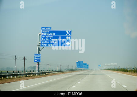 Uttar Pradesh, India. Agra to Delhi; Yamuna Expressway. Empty motorway with new blue bi-lingual signs in English and Hindi. Toll sign. Stock Photo