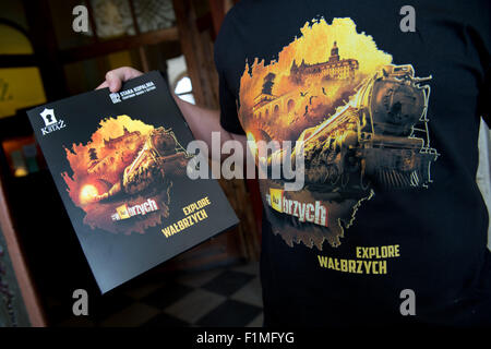 Tour guide Macciej Meissner, wearing a t-shirt which shows the depiction of a train and the writing 'Walbrzych' on it, holds a information booklet in his hands as he stands at the entrance area to former Fuerstenstein Palace (Ksiaz Palace), Walbrzych, Poland, 3 September 2015. A German tank train from World War II is believed to be located at a depth of 70 metres between mileage points 60 and 65 in an underground hideout near Ksiaz Palace. According to local legends, two tank trains, which have disappeared without traces in the last months of World War II, where hidden in the underground hide Stock Photo
