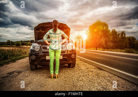 Woman on the road near the car. Damage to vehicle problems on the road. Stock Photo