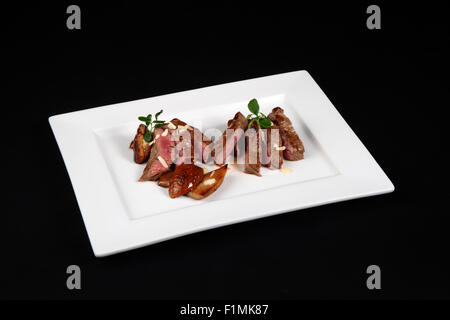 beef with mushrooms in white plate on a black background Stock Photo