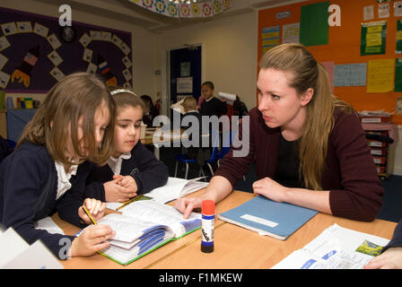 Primary school teacher helping pupil's in class, London, UK. Stock Photo