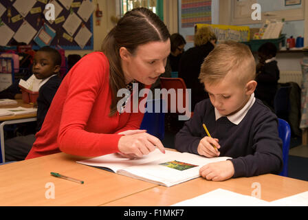 Primary school teacher assisting pupil in classroom, London, UK. Stock Photo