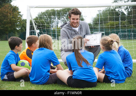 Coach Giving Team Talk To Elementary School Soccer Team Stock Photo