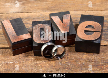 pair of wedding rings and the word Love written with vintage letterpress printing blocks Stock Photo