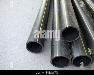 Black plastic PVC pipes on the street, a great bunch. Selective focus with shallow depth of field. Stock Photo