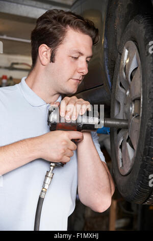 Mechanic In Garage Using Air Hammer On Car Wheel Stock Photo