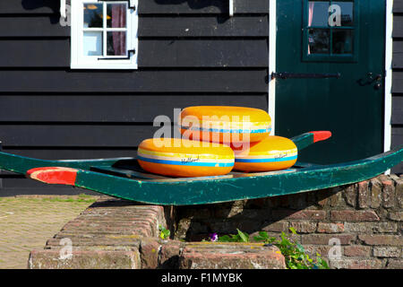 Dutch Cheese wheels on a green cart with farm house in the background Stock Photo