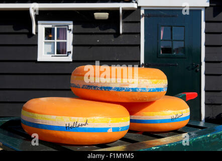 Dutch Cheese wheels on a green cart with farm house in the background Stock Photo