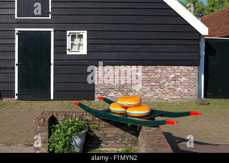 Dutch Cheese wheels on a green cart with farm house in the background Stock Photo