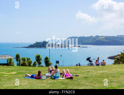 People sunbathing on the Hoe with Drake Island in the distance, Plymouth, Devon, England, UK Stock Photo