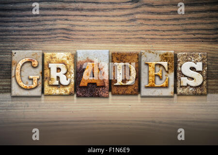 The word 'GRADES' written in rusty metal letterpress type sitting on a wooden ledge background. Stock Photo