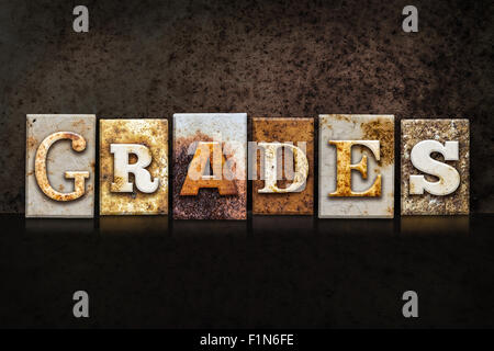 The word 'GRADES' written in rusty metal letterpress type on a dark textured grunge background. Stock Photo