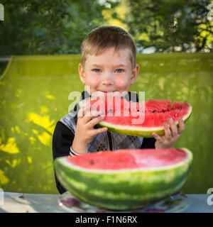 Little cute boy eats watermelon in the garden. Stock Photo