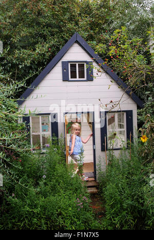 Lucy & Seb Tyler with their small wooden garden playhouse (wendy house) in Wiltshire,UK, a where they play with toys and bears. Stock Photo