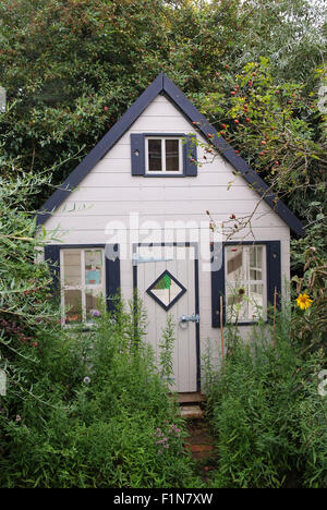 Lucy & Seb Tyler with their small wooden garden playhouse (wendy house) in Wiltshire,UK, a where they play with toys and bears. Stock Photo