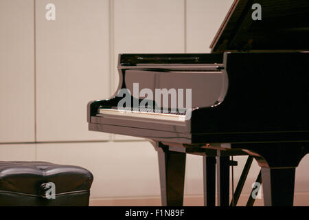 Glossy black grand piano with leather seat Stock Photo