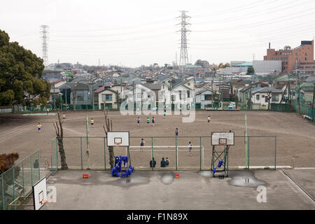 Japanese Junior High School Kids playing in dirt school field with basketball courts in foreground