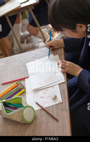 Japanese schoolgirl drawing with color pencils on wooden table Stock Photo