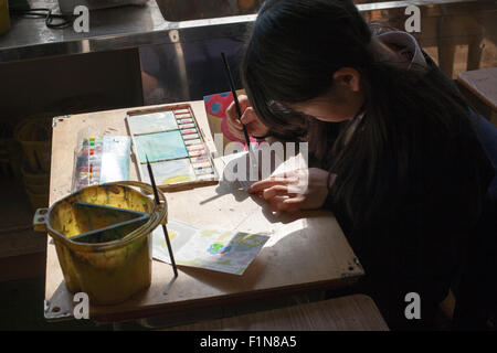 Japanese schoolgirl painting with water colors on wooden table Stock Photo