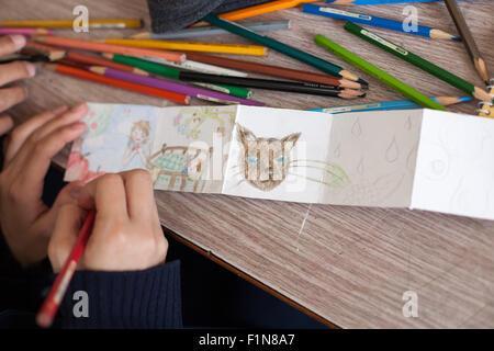 Girls hand drawing with color pencil on a white fold out card. Stock Photo