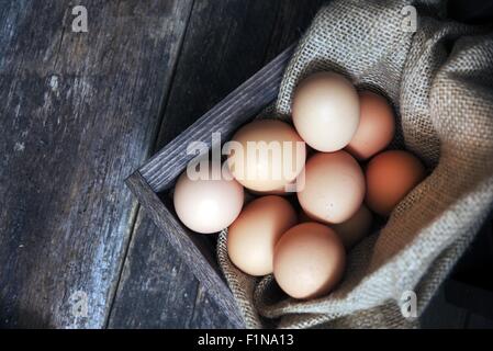 Fresh Eggs in Small Wooden Crate with Canvas on Aged Wooden Table. Fresh Organic Cage Free Chicken Eggs. Stock Photo