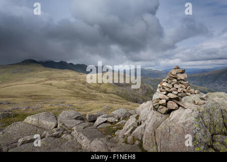 Cold Pike summit cairn looking across to the Crinkle Crags under a moody sky, in the English Lake District Stock Photo