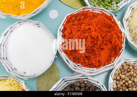 Grounded red salt in shiny bowls surrounded by other spices on a blue background Stock Photo