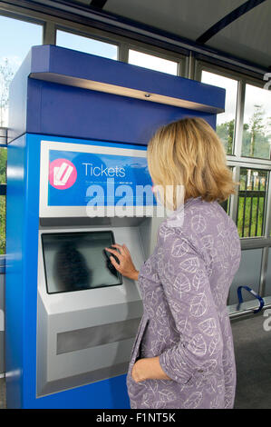 Woman buying rail ticket from a ticket machine at a station, UK Stock Photo