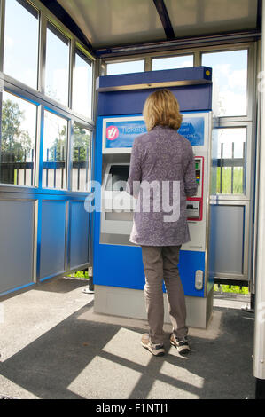 Woman buying rail ticket from a ticket machine at a station, UK Stock Photo