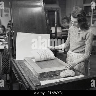 Historical, 1950s, picture shows a female worker using traditional methods to produce a print. Stock Photo
