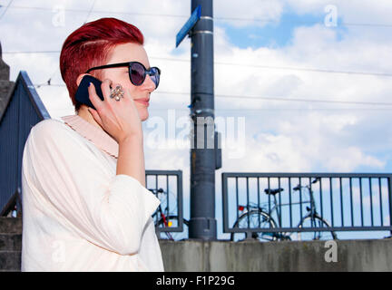 red-haired woman standing outside and talking on the phone Stock Photo