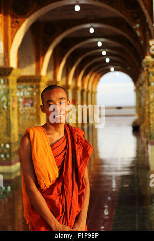 Buddhist monk at the Sutaungpyei Pagoda in Mandalay, Myanmar. The monk stands under one of the temple's arches. Stock Photo