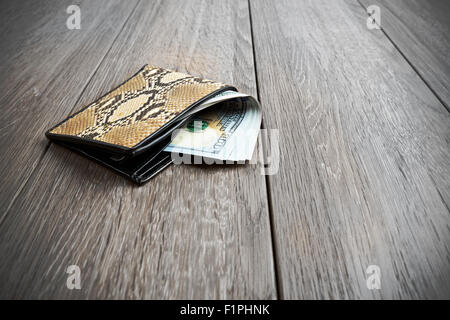 snake leather wallet with money on wooden background Stock Photo