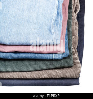stack of different jeans and corduroys close up isolated on white background Stock Photo