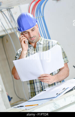 Builder checking with a colleague over the phone Stock Photo