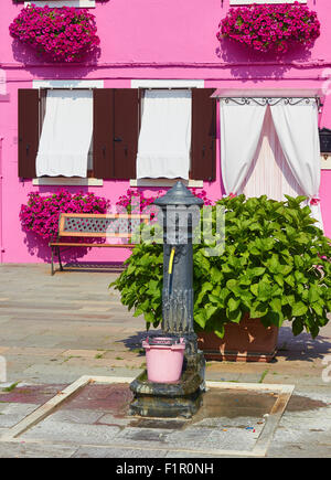 Lion head water fountain in front of pretty pink Burano house Venetian Lagoon Veneto Italy Europe Stock Photo