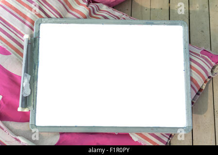 White plastic slate with blank space on a pink pillow on a wooden flooring Stock Photo