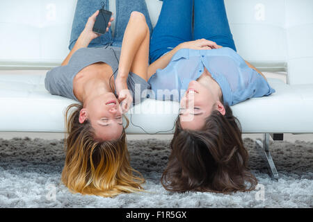 Teenagers upside down on sofa, listening to music Stock Photo