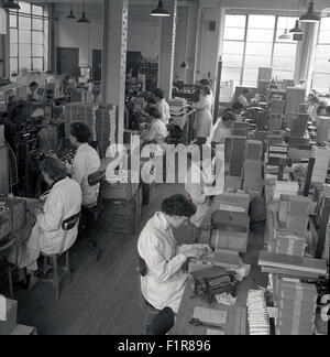 Historical, 1950s, female workers in white-coats sit at benches sorting and packaging up boxes of medical supplies. Stock Photo