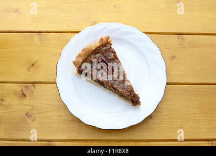 Portion of traditional pecan pie on a white plate on a wooden table Stock Photo