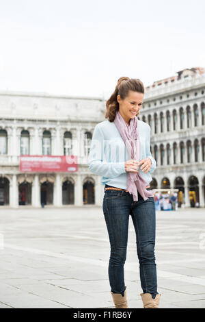 Strolling along through an almost-empty St. Mark's Square in Venice, an elegant woman smiles to herself, loving the feeling of a Stock Photo