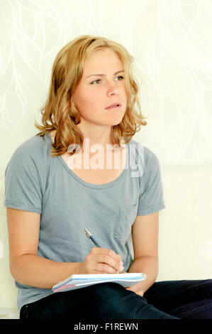 Young woman thinking over making notes in notebook Stock Photo